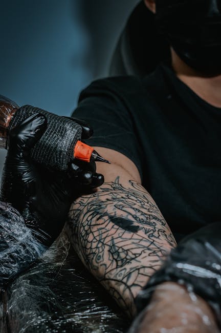 Tatuador trabajando en un intrincado diseño de brazo en primer plano